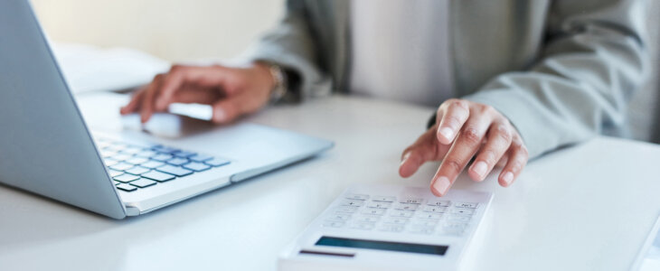 Closeup shot of an unrecognisable businesswoman using a calculator and laptop in an office
