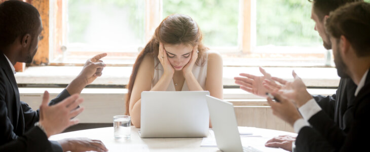 Male colleagues pointing fingers at upset female boss on meeting, tired sad woman leader experiencing gender discrimination at work, businessmen blaming bullying depressed businesswoman for mistake