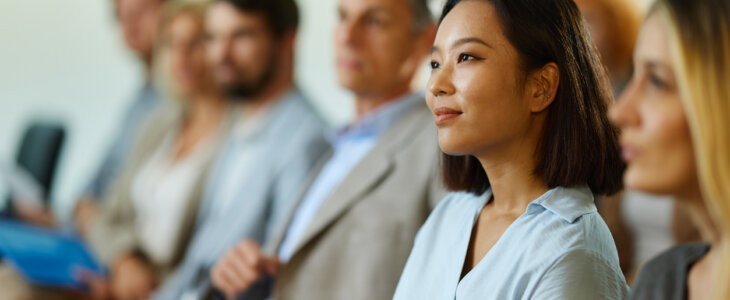 Young smiling Chinese businesswoman and her colleagues attending an education event in the office.