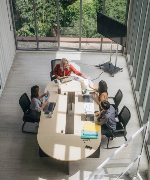 Overhead view of four people having a meeting in a bright, modern office.